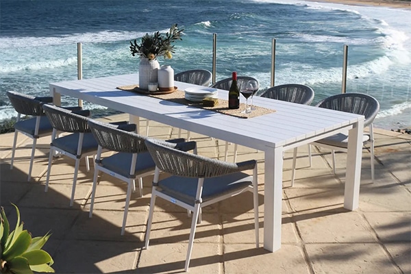 modern outdoor dining set with a long white table and eight grey woven chairs
