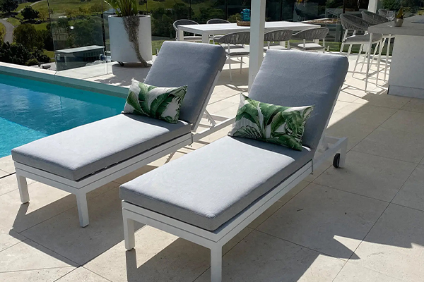 Pair of sun loungers along side a swimming pool.