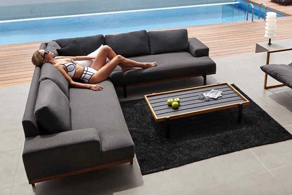 woman lounges on a modern dark grey l shaped outdoor sofa